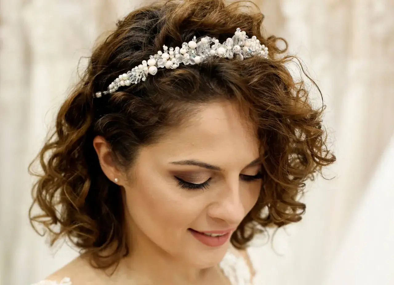 Brautfrisur kurze haare bob mit einem glitzernden Diadem. Lockige Haare umrahmen das Gesicht einer l&auml;chelnden Braut.