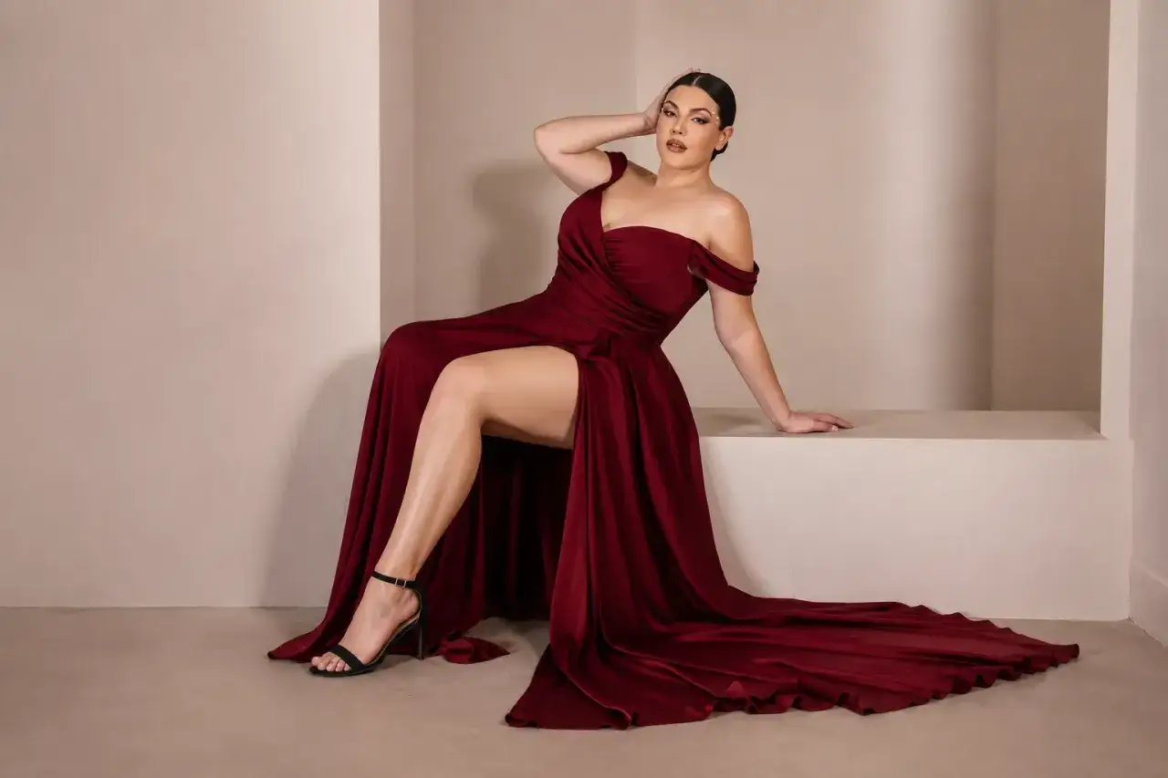 Frau in einem eleganten, weinroten Abendkleid mit hohem Beinschlitz, das die neuesten Dresscodes für Frauen verkörpert.
