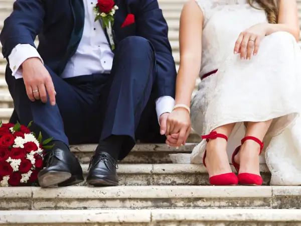 Brautpaar hält Händchen, rote Rosen & Schuhe. Perfekt für Ideen kleine standesamtliche hochzeit.