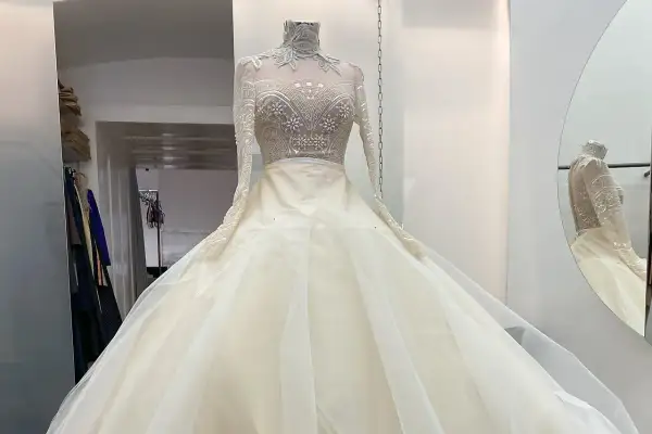 Ein prachtvolles, elfenbeinfarbenes Brautkleid mit einem hochgeschlossenen, bestickten Oberteil und einem voluminösen Tüllrock. Dieses Kleid könnte das Hochzeitskleid einer Kaiserin sein.