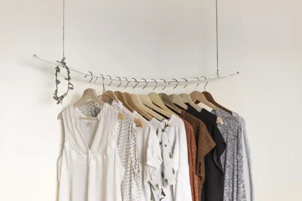 Eine Auswahl an Kleidungsstücken, die eine minimalistische capsule wardrobe bilden könnten, hängt an einer Garderobenstange.