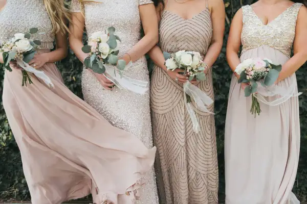 Brautjungfern in eleganten Kleidern mit Blumensträußen, perfekt für einen dresscode boho hochzeit.