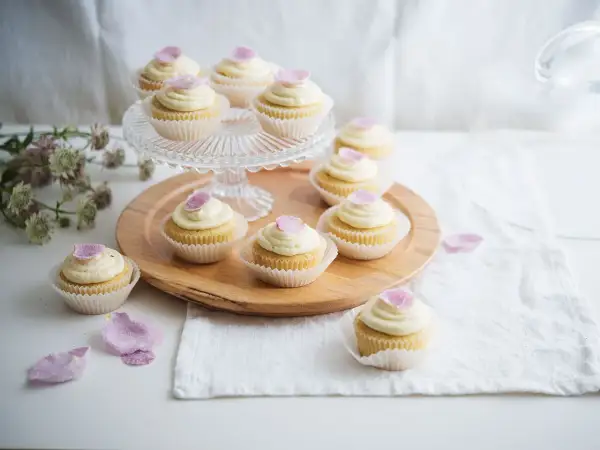 Zarte Cupcakes mit cremiger Glasur und rosa Blütenblättern – süße Ideen für eine Hochzeit.