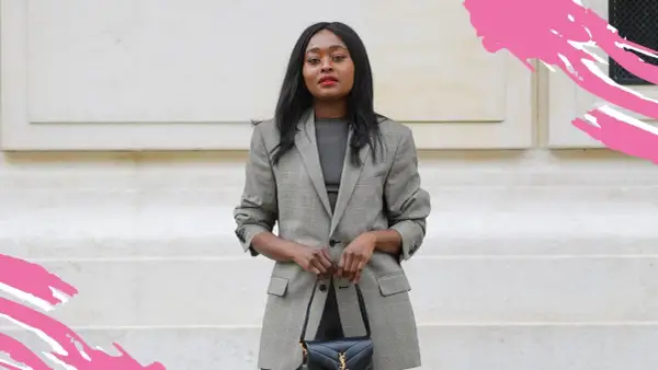 Frau in kariertem Blazer und dunklem Oberteil, perfekt für einen **business casual** Look, hält eine schwarze Handtasche.