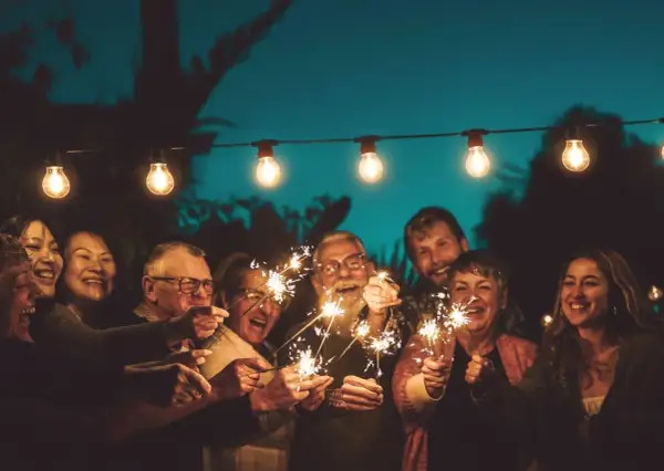 Familie feiert mit Wunderkerzen unter Lichterketten. Ein Lächeln, das die Bedeutung eines 75. Hochzeitstages widerspiegelt.